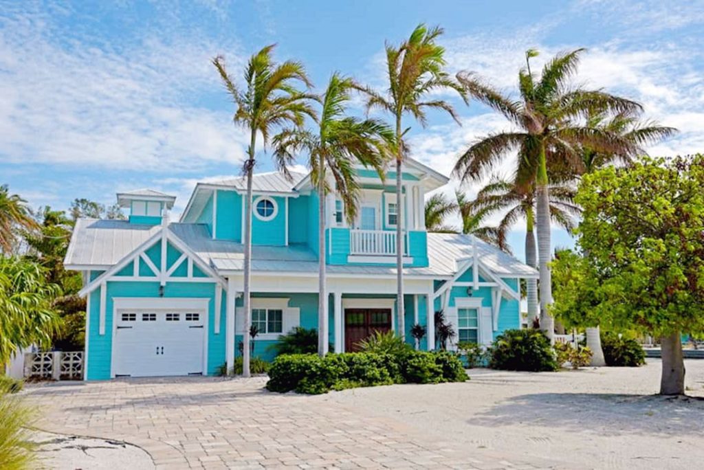 Turquoise blue beach home exterior color surrounded by palm trees
